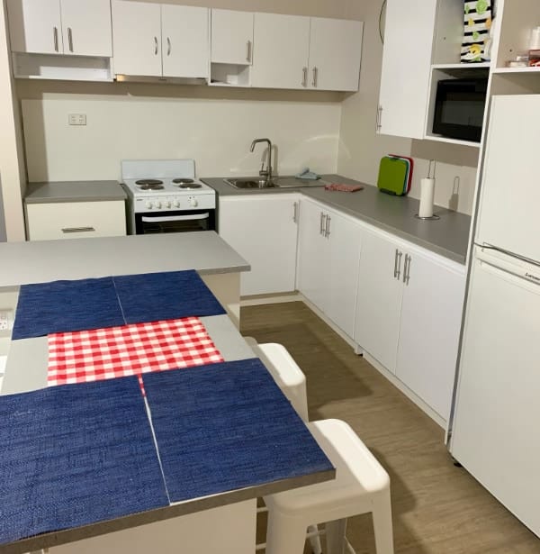 The shared kitchen has everything you need, including a fridge/freezer, stovetop, oven, and microwave. There’s an island bench, surrounded by barstools.